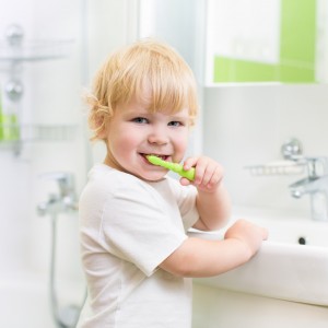 Kid boy brushing teeth in bathroom